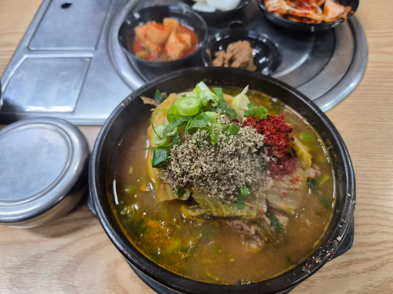 뚝배기에 담긴 뼈다귀탕 위에 들깨가루와 고춧가루가 뿌려진 모습