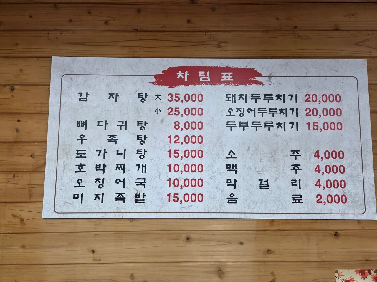 나무 벽면에 부착된 시골해장국의 정직한 가격이 적힌 차림표